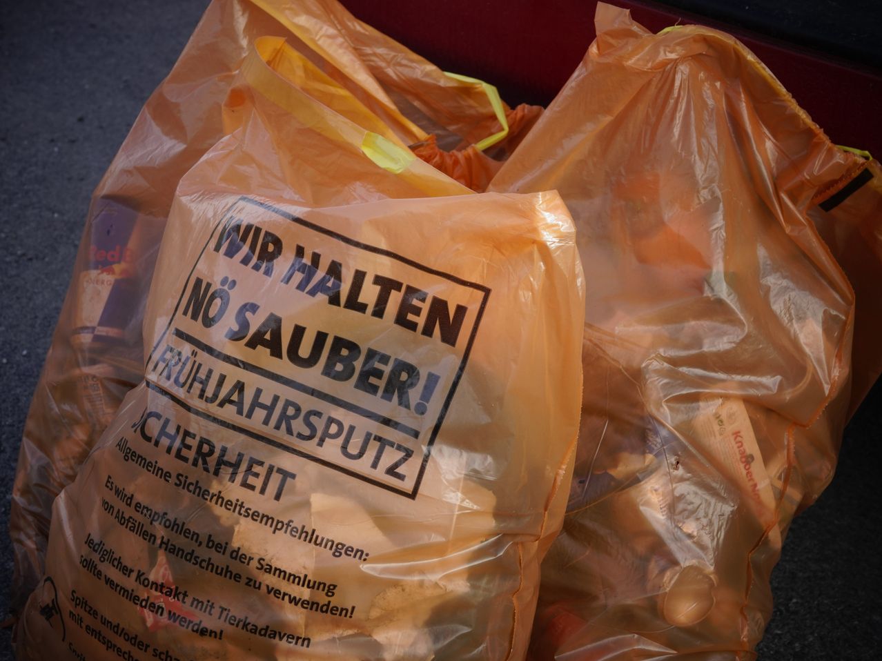 Ein Stapel durchsichtiger Plastiktüten mit einem Aufkleber. Der Aufkleber besagt: 'Wir halten no sauber! Fruhjahrsputz Sicherheit.'