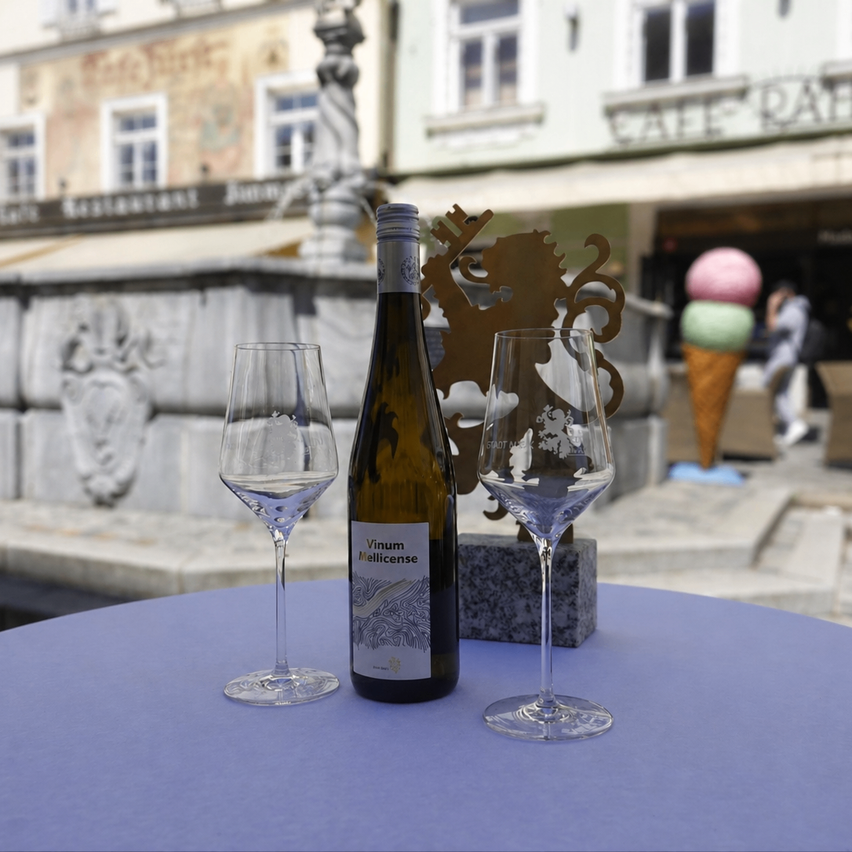 Eine Flasche Wein, zwei Weingläser und ein Eisbecher stehen auf einem Tisch vor einem Restaurant.