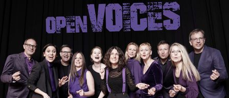 Eine Gruppe von Menschen in lila Kleidung posiert für ein Foto vor einer Bühnenkulisse mit den Worten 'PEN VOICES' in fetten Buchstaben.