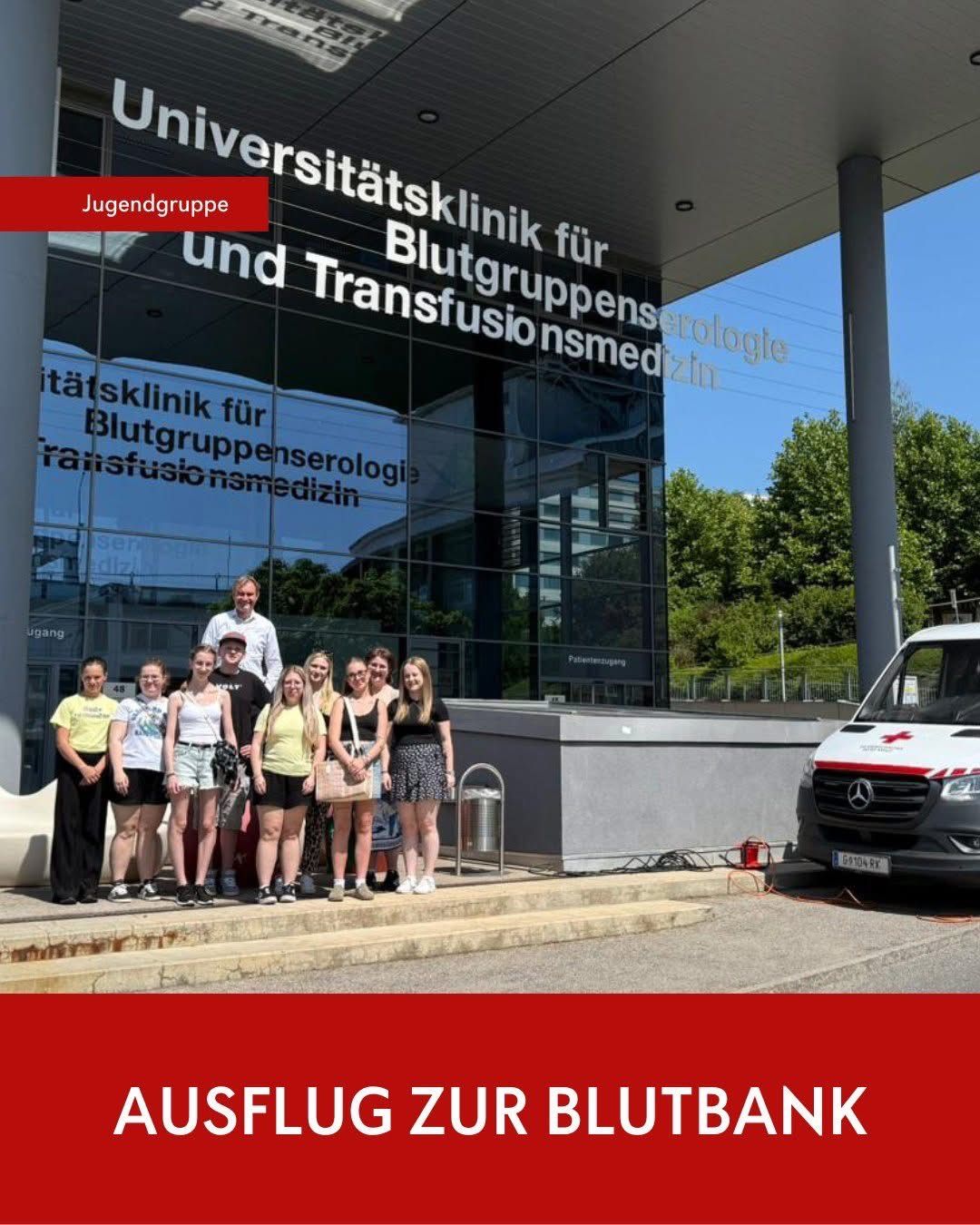 Eine Gruppe von Menschen steht vor einem Gebäude, das als Universitätsklinik für Blutgruppenserologie und Transfusionsmedizin gekennzeichnet ist. Das Schild trägt den Schriftzug Jugendgruppe. Ein weißer Van ist seitlich geparkt.