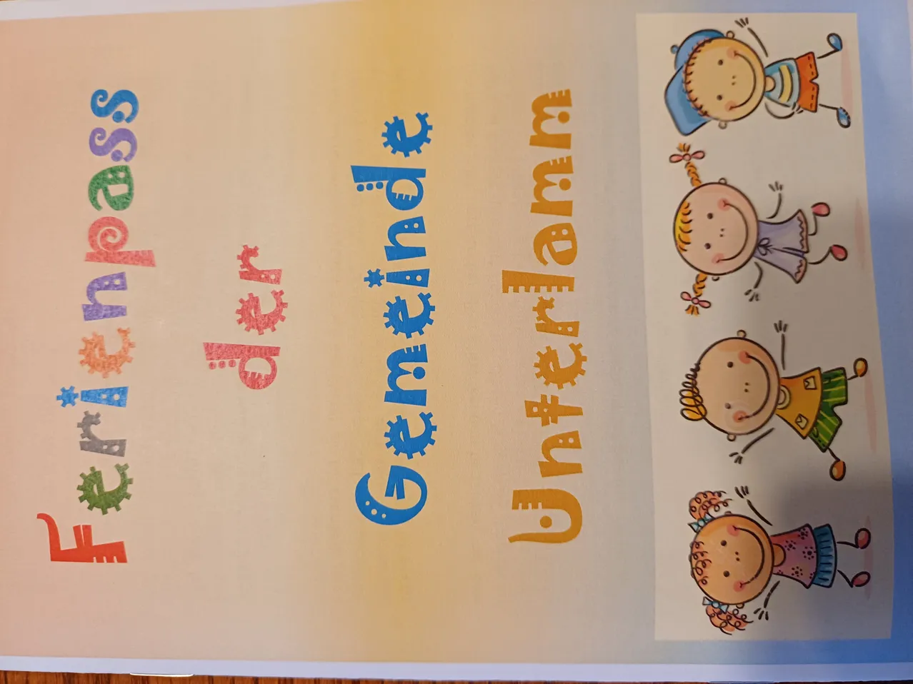 Ein offenes Buch mit dem Titel Gemeinschaft auf dem Cover. Das Buch zeigt farbenfrohe Illustrationen von Kindern in verschiedenen Posen.