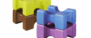Vier ineinandergreifende Schaumstoffblöcke in Gelb, Grün, Blau und Lila, die auf einem weißen Hintergrund gestapelt sind.