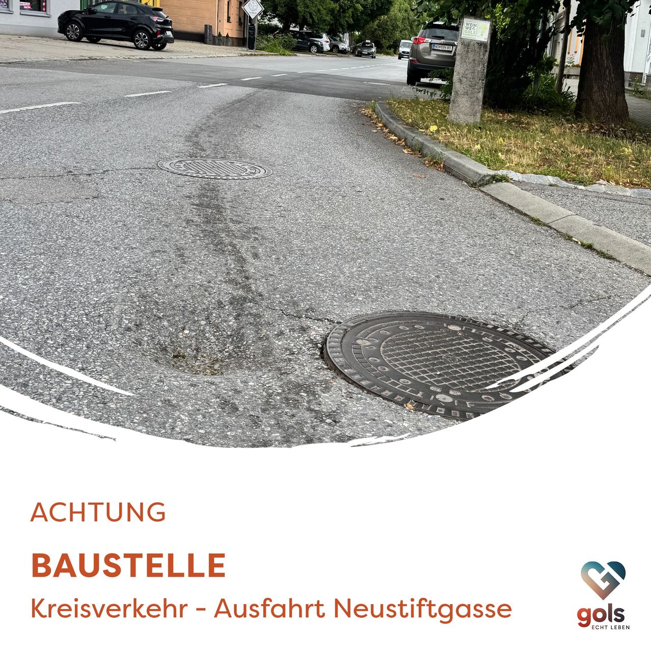 Ein Bild, das eine Straße mit einem Warnschild zeigt, das auf Bauarbeiten hinweist. Zwei Autos sind geparkt, und es gibt Schachtdeckel auf der Straße. Das Schild steht für 'ACHTUNG BAUSTELLE'.