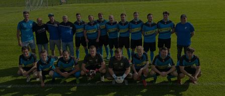 A soccer team is posing for a photo on a field, with three soccer balls in the background. The text reads 'Home Games - Tragös - St. Katharina.' The date is April 11, 2020, at 17:00.