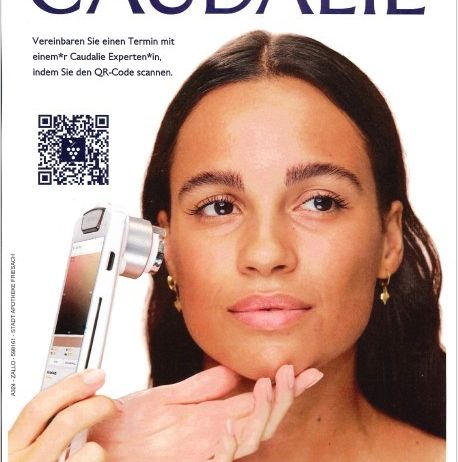 Eine Frau benutzt ein weißes Dermatoskop an ihrem Gesicht und schaut direkt in die Kamera, mit einem QR-Code in der oberen linken Ecke und dem Markennamen Caudalie über ihr.