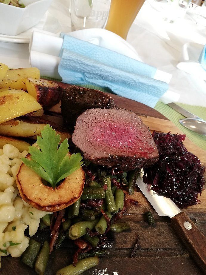 Eine Mahlzeit mit gebratenen Kartoffeln, grünen Bohnen und Rindersteak liegt auf einem Holzschneidebrett.