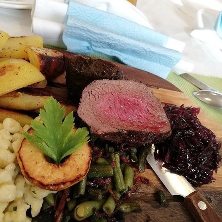 Eine Mahlzeit mit gebratenen Kartoffeln, grünen Bohnen und Rindersteak liegt auf einem Holzschneidebrett.