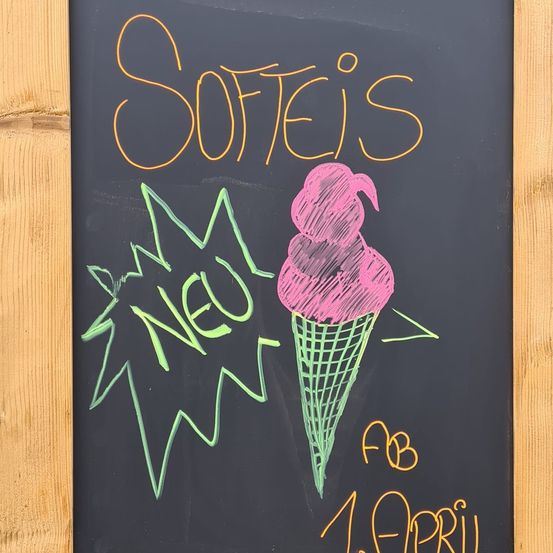 Schraubtafel mit Kreideschrift, die neue Softeis ab dem 1. April ankündigt. Illustration eines Eisbechers.