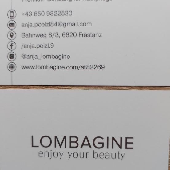 Eine weiße Visitenkarte mit Kontaktinformationen für Lombagine. Sie enthält eine Telefonnummer, E-Mail, Adresse und Social-Media-Handles. Der Slogan lautet 'Genießen Sie Ihre Schönheit'.