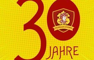 Ein gelber Hintergrund mit einem roten kreisförmigen Emblem und '30 Jahre' in fetter roter Schrift. Das Emblem hat einen Schild und die Zahl '30' auf der linken Seite.