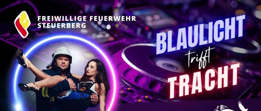 Ein Bild eines Mannes und einer Frau, der Mann als Feuerwehrmann verkleidet, trägt die Frau auf seinem Rücken, vor dem Hintergrund eines DJ-Setups mit 'Blaullicht trifft Trachten' in weiß geschrieben.