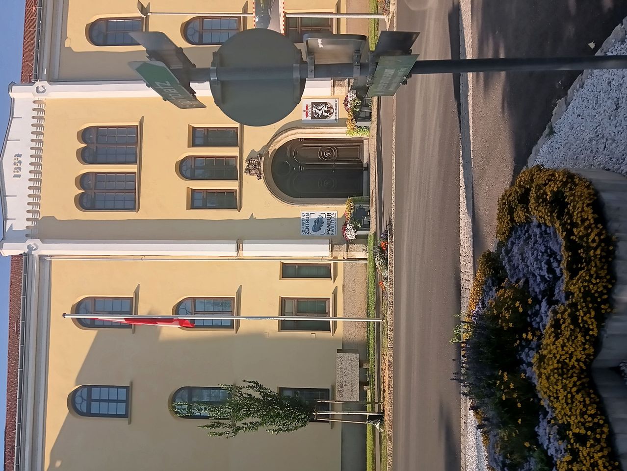 A top-down view of a building with multiple arched windows and a flagpole. The building has a sign that reads 'Zentralstrasse'.