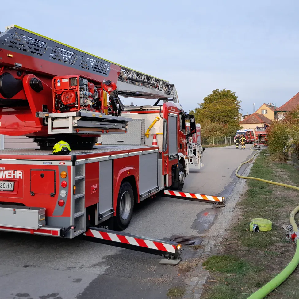 Ein roter Feuerwehrwagen mit ausgefahrener Leiter steht am Straßenrand.