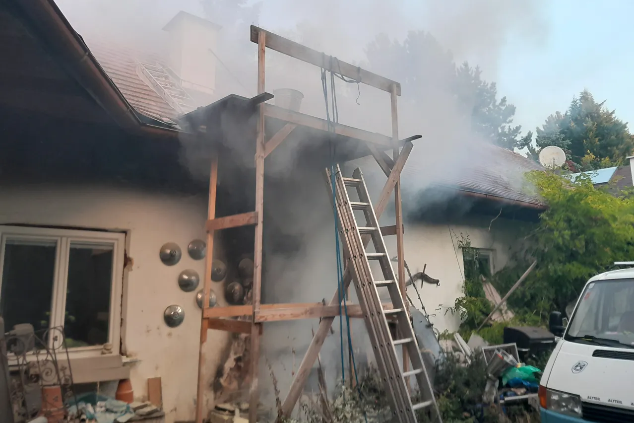 Ein Haus mit einer Holzkonstruktion auf dem Dach, die Rauch abgibt.