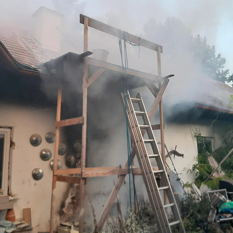 Ein Haus mit einer Holzkonstruktion auf dem Dach, die Rauch abgibt.