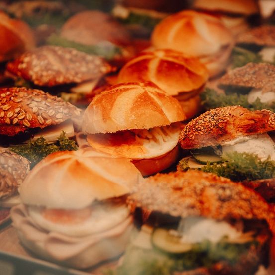 Ein Nahaufnahme von verschiedenen Sandwiches mit unterschiedlichen Belägen und Füllungen, die in einer Bäckerei ausgestellt sind.