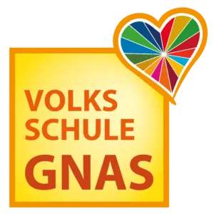 Ein gelbes Schild mit einem bunten Herz darüber. Der Schriftzug 'VOLKSSCHULE GNAS' ist in roter und weißer Schrift geschrieben.
