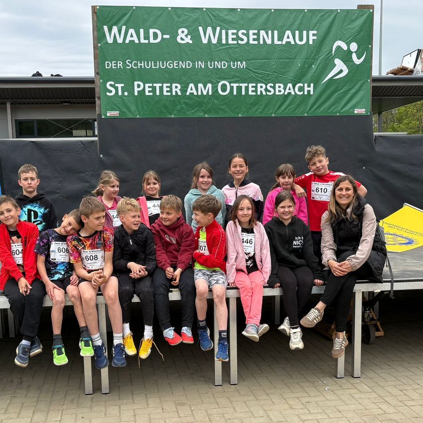 Eine Gruppe von Kindern und einer Frau posiert vor einem Banner mit dem Text 'WALD-& WIESENLAUFST. PETER AM OTTERSBACH'.