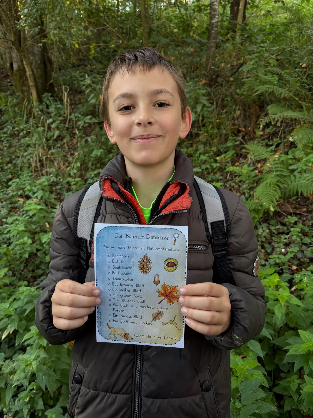Ein Junge im Wald hält ein Papier mit einer Liste von Gegenständen, die er finden muss.