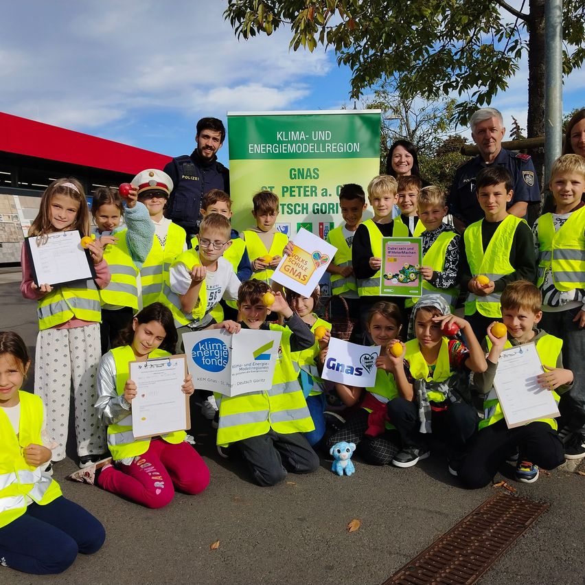 Eine Gruppe von Kindern und Erwachsenen posiert für ein Foto vor einem grünen Banner mit den Worten Klima- und Energiemodellregion und Gnas Peter a. Dtsch Gori.