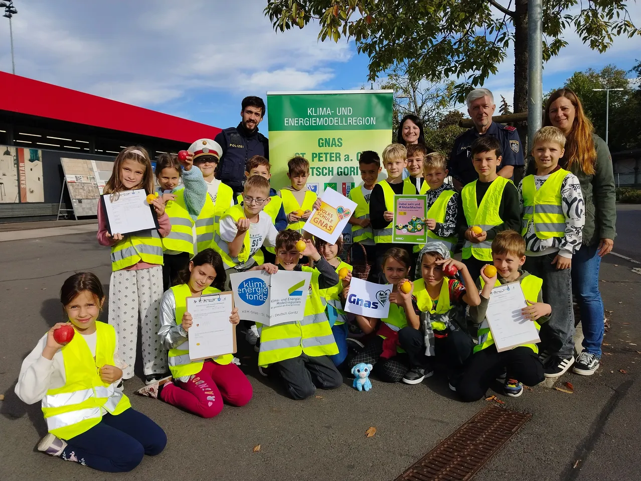 Eine Gruppe von Kindern und Erwachsenen posiert für ein Foto vor einem grünen Banner mit den Worten Klima- und Energiemodellregion und Gnas Peter a. Dtsch Gori.