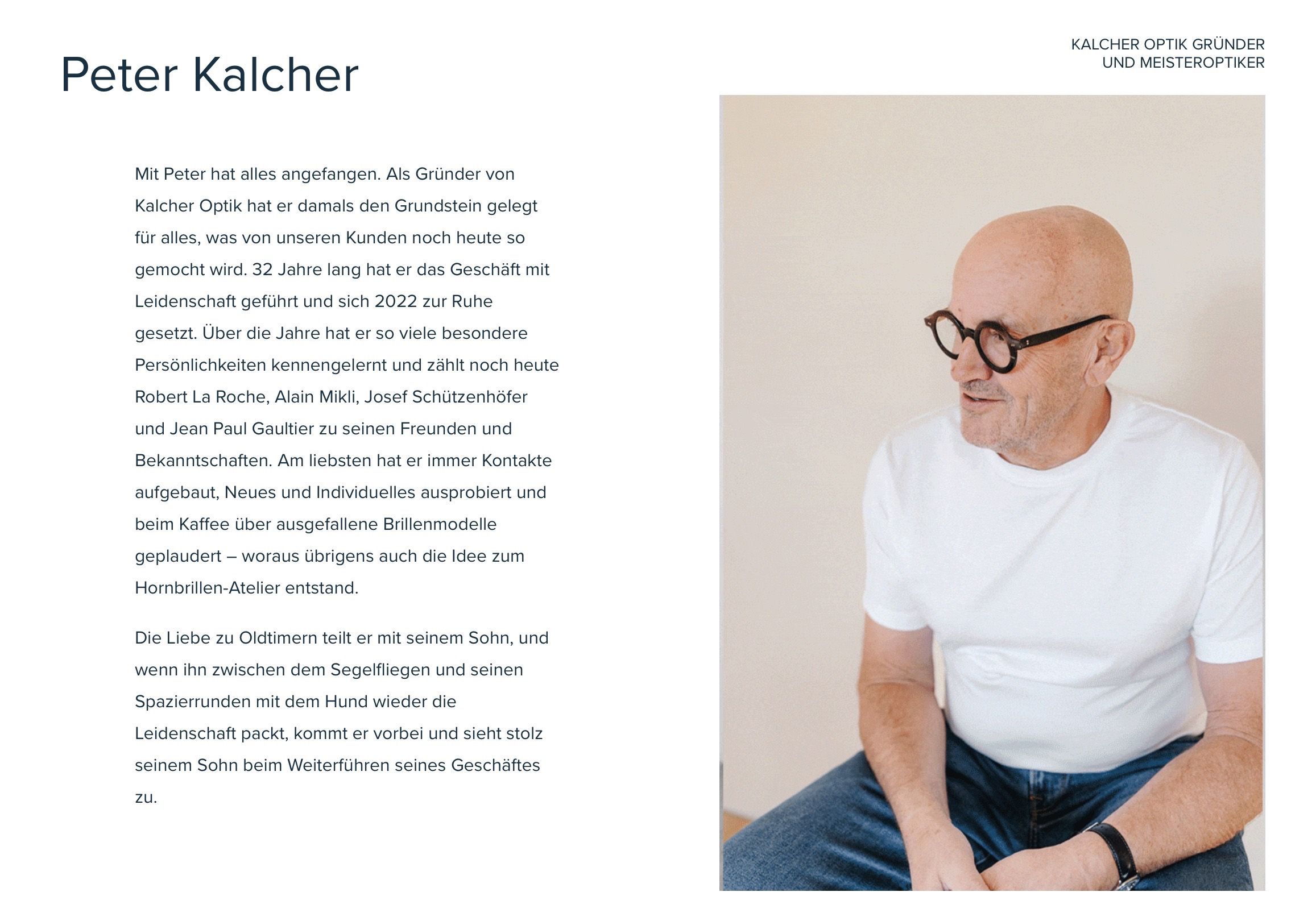 Ein Mann mit Brille sitzt in einem Stuhl, trägt ein weißes Hemd und blaue Jeans. Er lächelt und scheint sich in einem professionellen Umfeld zu befinden.