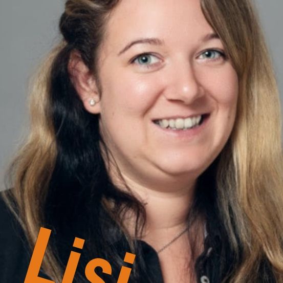 Eine lächelnde Frau mit blonden und schwarzen Haaren, die ein schwarzes Hemd und eine Halskette trägt, posiert für ein Foto. Ihr Name 'Lisi' ist in orange Buchstaben angezeigt.
