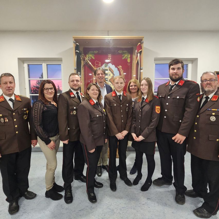 Eine Gruppe von Menschen in Militäruniformen posiert für ein Foto in einem Raum mit einer Fahne.