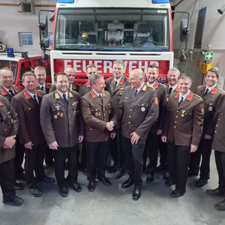 Mehrere Männer in Militäruniformen posieren für ein Foto vor einem Feuerwehrauto. Das Wort Feuerwehr steht auf der Vorderseite des Autos.