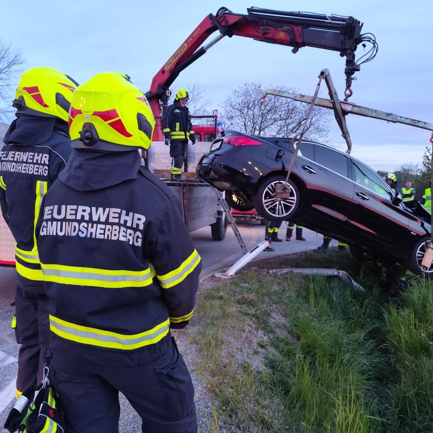 Feuerwehrleute verwenden einen Kran, um ein auf der Seite liegendes Auto anzuheben.
