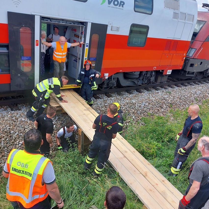 Feuerwehrleute und Freiwillige bauen eine Holzrampe, damit die Passagiere aus einem entgleisten Zug aussteigen können.