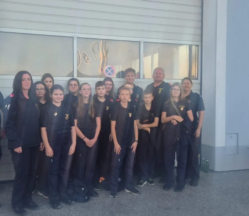 Eine Gruppe von Menschen in Uniform, einschließlich Männer und Frauen, stehen vor einem Gebäude.