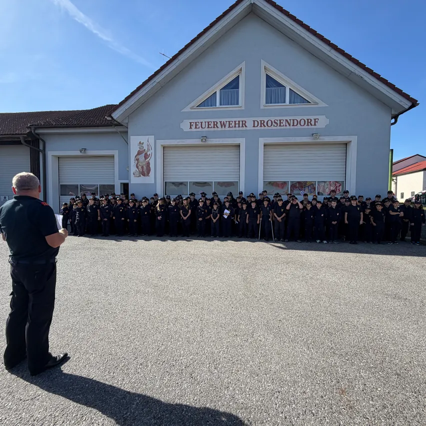 Eine Gruppe von Feuerwehrleuten in Uniform steht vor einem Feuerwehrhaus.