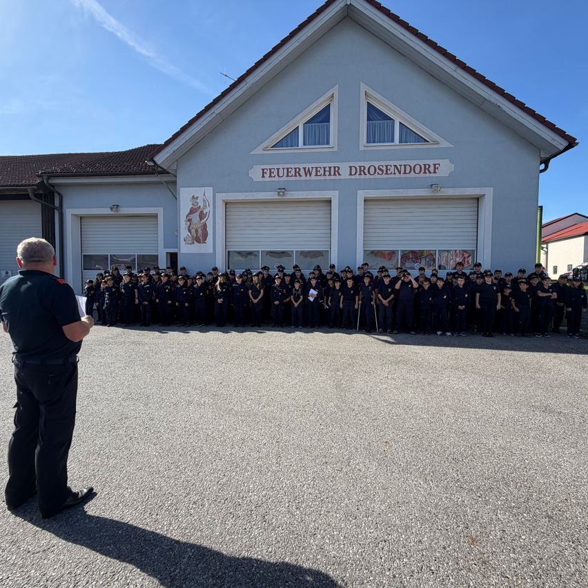 Eine Gruppe von Feuerwehrleuten in Uniform steht vor einem Feuerwehrhaus.