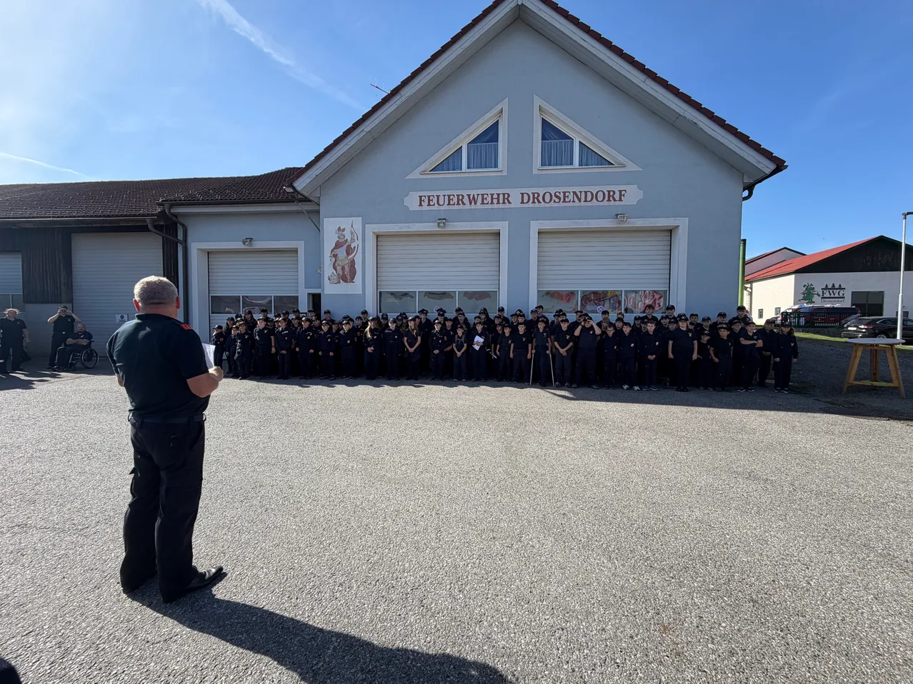 Eine Gruppe von Feuerwehrleuten in Uniform steht vor einem Feuerwehrhaus.