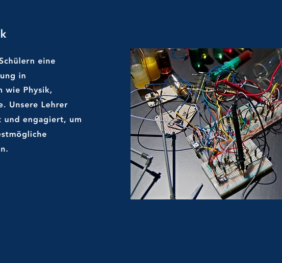 Ein Bild aus dem Wissenschafts- und Techniklabor einer Schule. Ein unordentlicher Arbeitsplatz ist sichtbar, mit verstreuten elektronischen Komponenten, Kabeln und Werkzeugen.