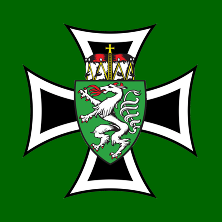 Das Emblem zeigt einen weißen Löwen auf einem grünen Schild mit einem roten Kamm oben, vor einem grünen Hintergrund. Der Schild ist von einem weißen Kreuz mit schwarzen Rändern eingerahmt.