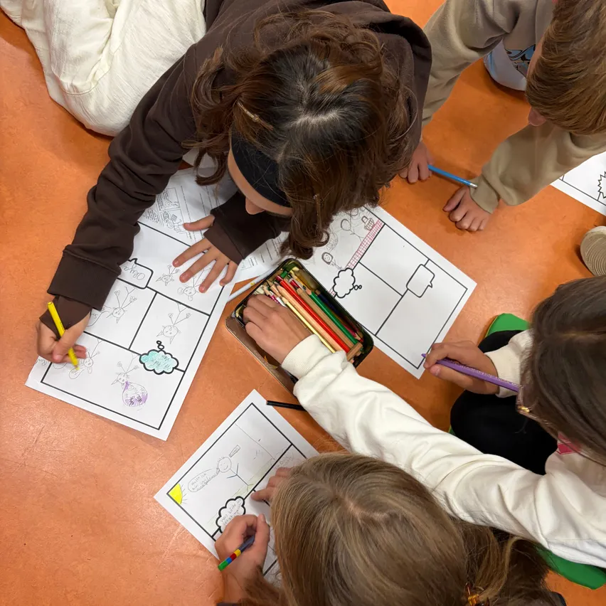 Eine Gruppe von Kindern sitzt auf dem Boden und füllt eine Comic-Seite mit verschiedenen farbigen Stiften aus.