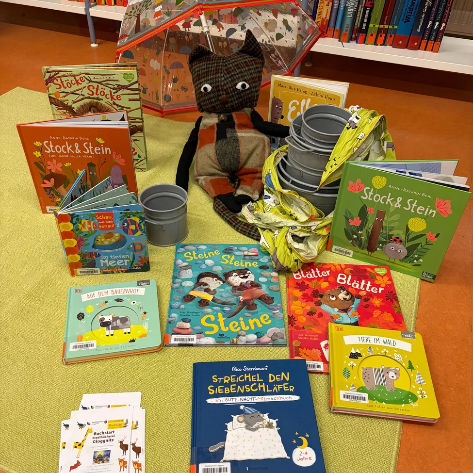 Eine Sammlung von Kinderbüchern und einem Plüschtier auf einem grünen Teppich.