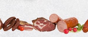 Eine Auswahl an Fleischsorten wird gezeigt, einschließlich Würste, Speck und Aufschnitt, alles begleitet von Tomaten und Radieschen auf weißem Hintergrund.