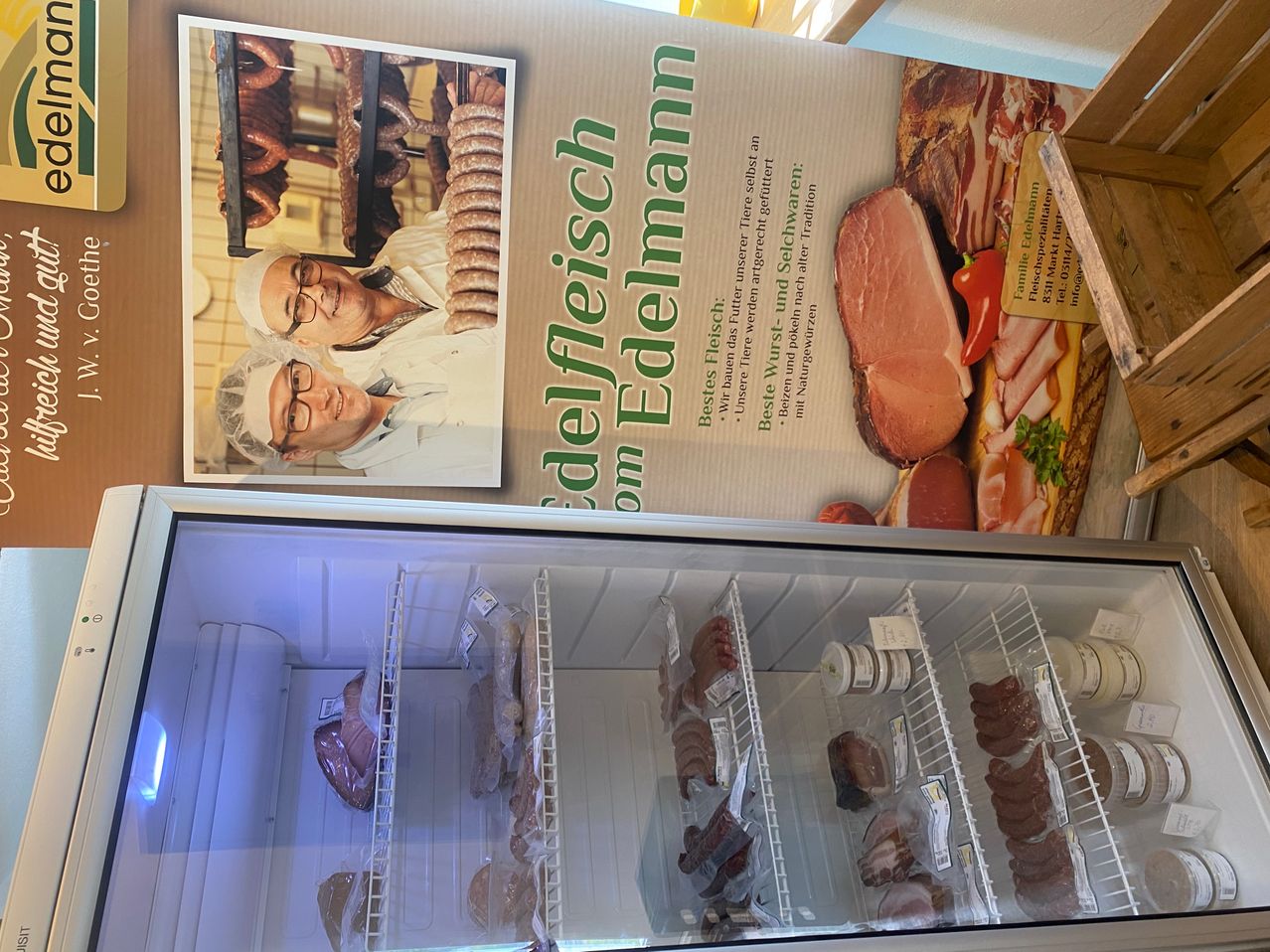 Eine Werbung für Edelfleisch auf Edelmann zeigt zwei Männer in einer Fleischverarbeitungsabteilung. Darunter befindet sich ein gekühlter Tresen mit verschiedenen Fleischsorten.