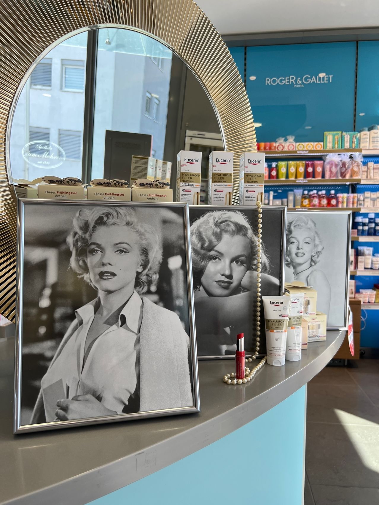 Eine Ausstellung von Kosmetik- und Hautpflegeprodukten in einem Schönheitssalon. Ein Schwarz-Weiß-Foto von Marilyn Monroe steht auf dem Tresen.