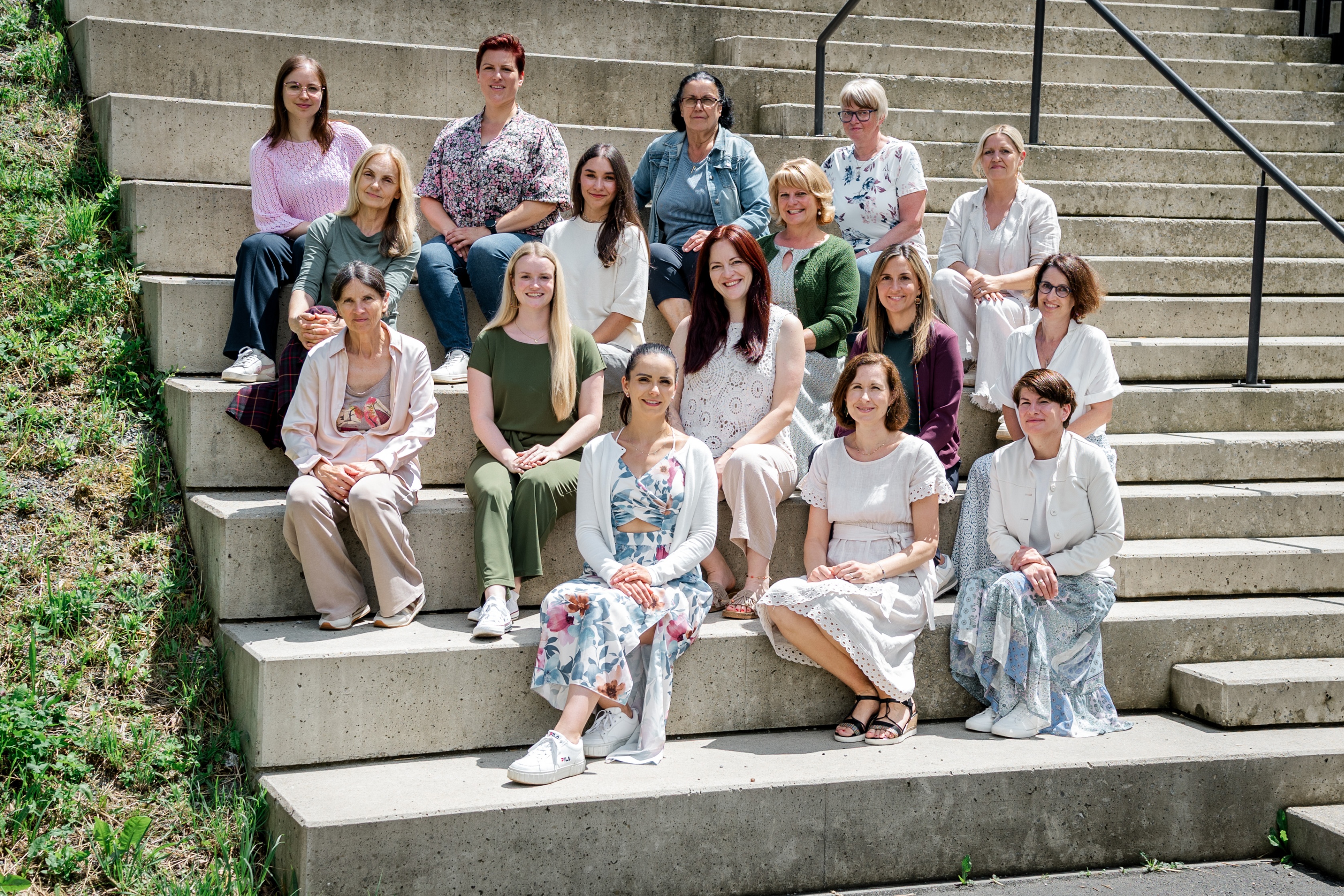Eine Gruppe von Frauen sitzt auf einer Treppe und lächelt für ein Foto.