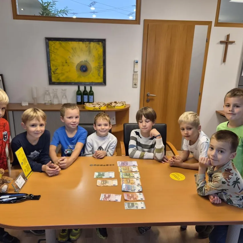 Eine Gruppe junger Jungen sitzt um einen Tisch mit Geld und einem Teddybär.