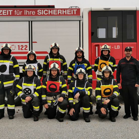 Bild enthält, People, Person, Truck, Vehicle, Car, Wheel, Fire Truck, Fire Station, Helmet, Coat