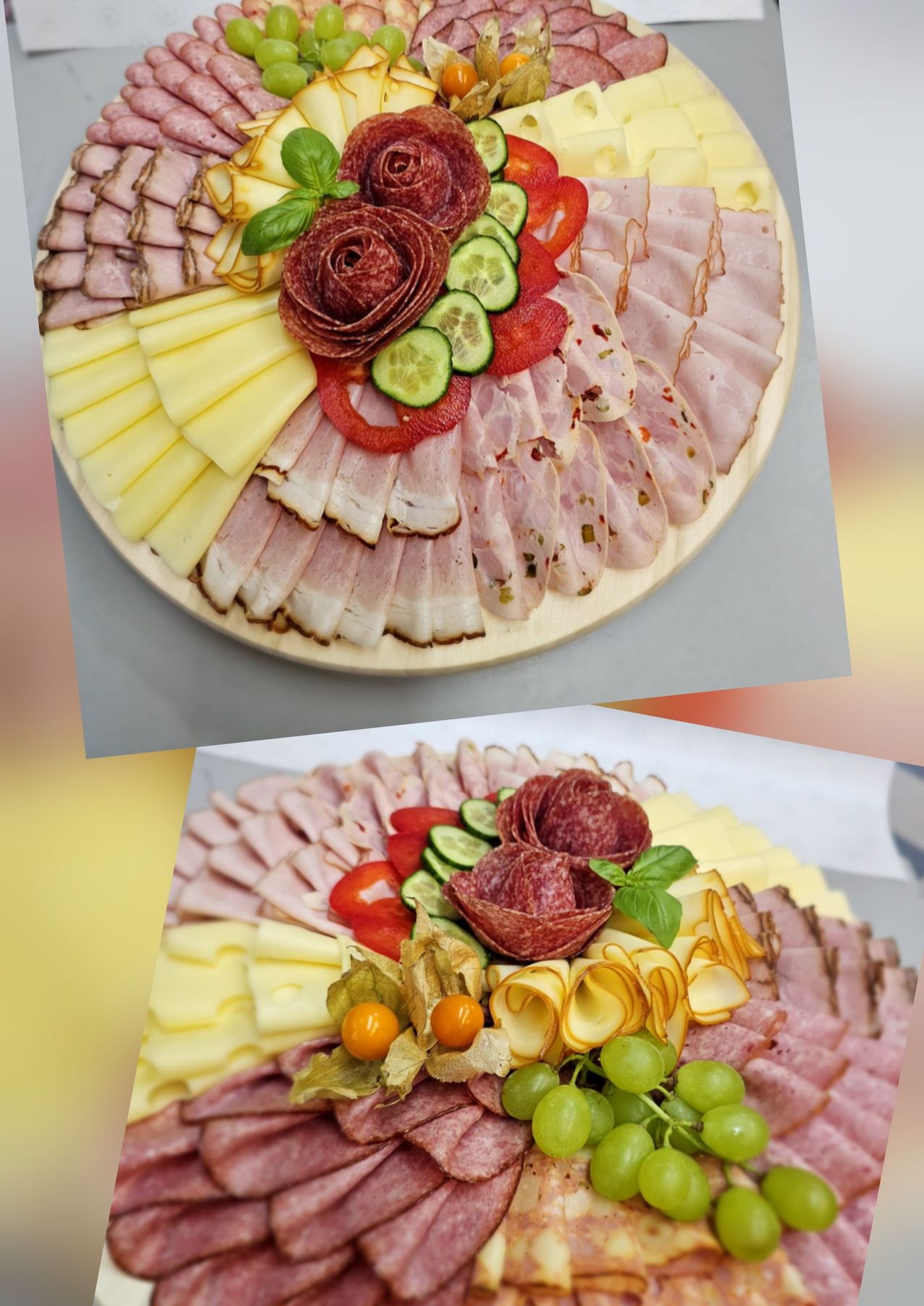 Ein Holztablett zeigt eine Vielzahl von Fleisch, Käse und Gemüse kunstvoll arrangiert. Das Tablett enthält Scheiben von Schinken, Käse und Gurken, mit Kirschtomaten und Basilikumblättern als Farbtupfer. Darunter befindet sich ein weiteres Tablett mit ähnlichem Inhalt, einschließlich Trauben.