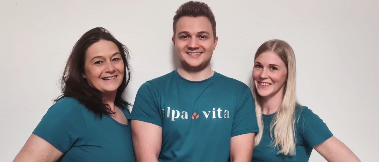 Drei Personen, zwei Frauen und ein Mann, posieren für ein Foto. Sie tragen alle passende türkisfarbene T-Shirts. Der Mann hat ein Logo auf seinem Shirt.