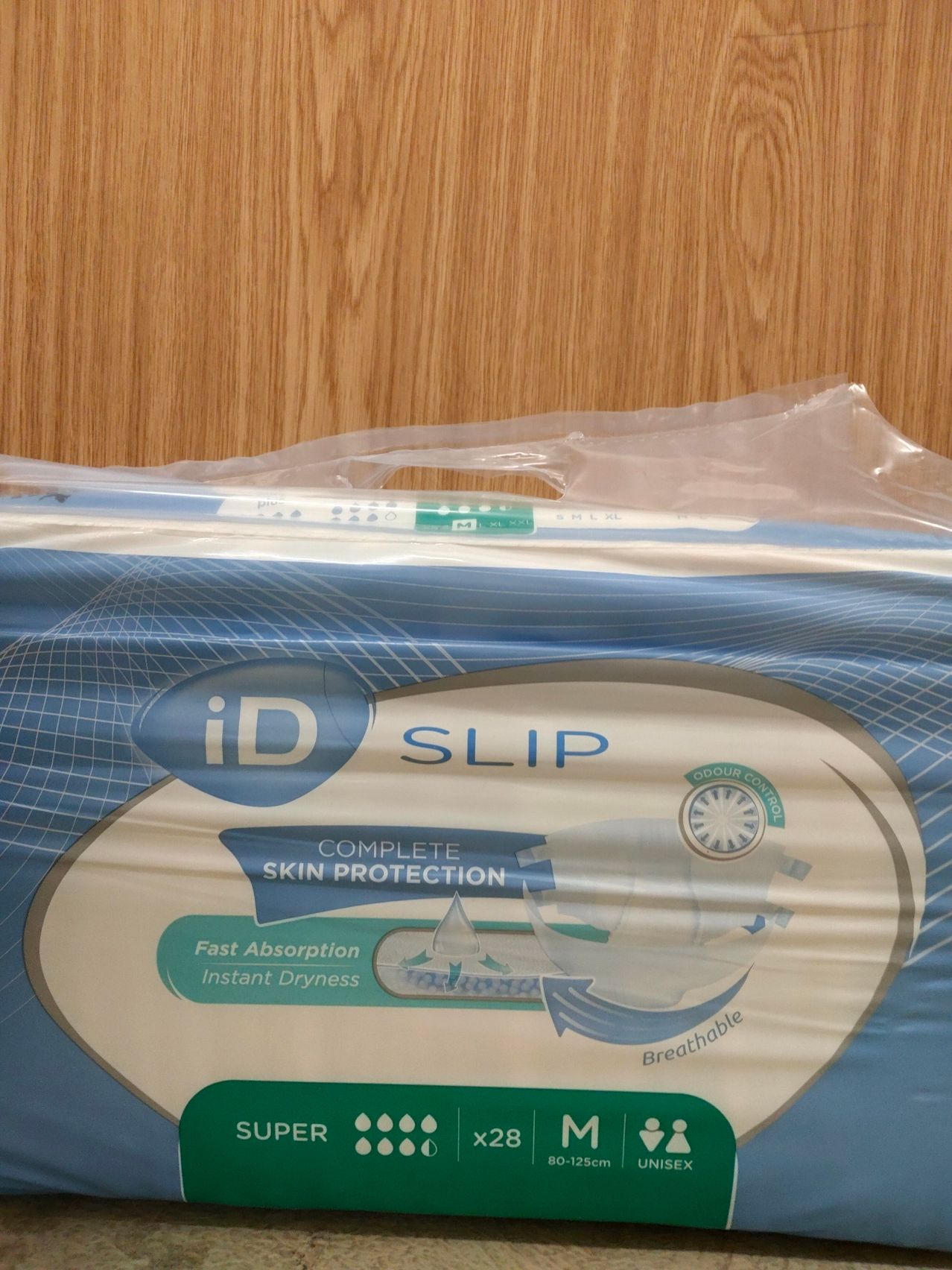Eine Packung iD Slip Inkontinenzunterlagen, die vollständigen Hautschutz, schnelle Absorption und sofortige Trockenheit bietet. Die Packung ist in Plastik versiegelt.