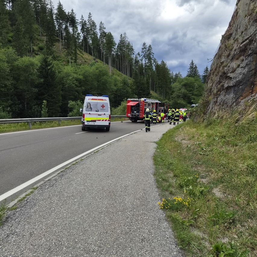 An ambulance and a fire truck are parked on the side of a road. Emergency personnel are attending to an accident.