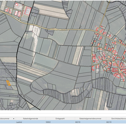 Eine Karte eines ländlichen Gebiets mit Feldern und einer Siedlung. Die Siedlung ist mit roten Linien hervorgehoben. Es umfasst verschiedene Infrastrukturen wie Straßen, Gebäude und eine durch eine gelbe Linie gekennzeichnete Grenze.